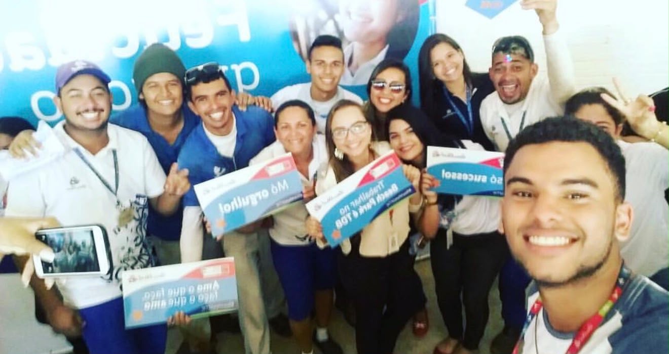 Raissa Bisol com a equipe do Beach Park segurando placas de orgulho por trabalhar no parque